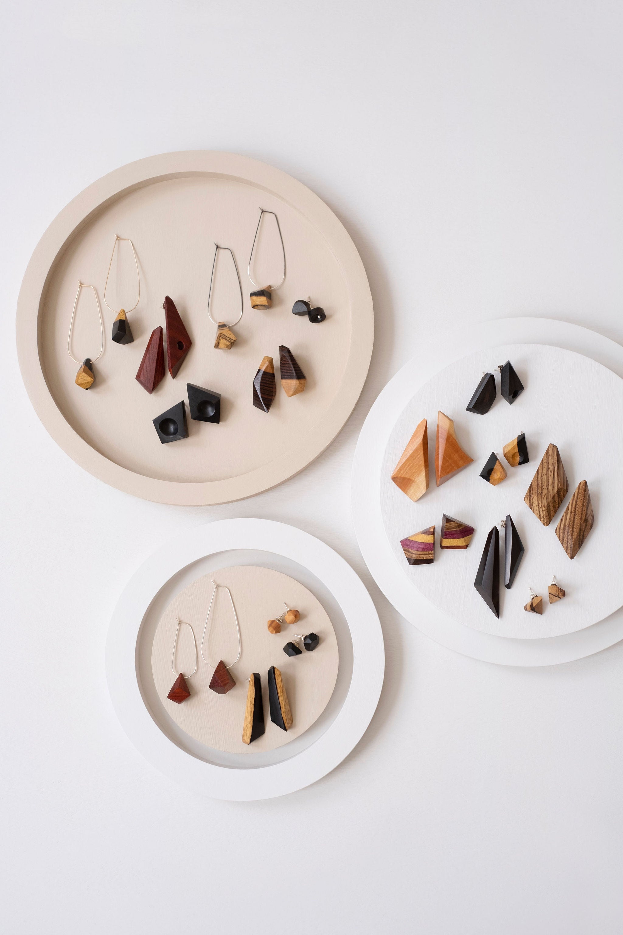 3 Round displays, off white background with various wood earrings on the displays. 