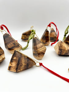 Wooden geometric ornaments with brass details and red and green strings on a white background