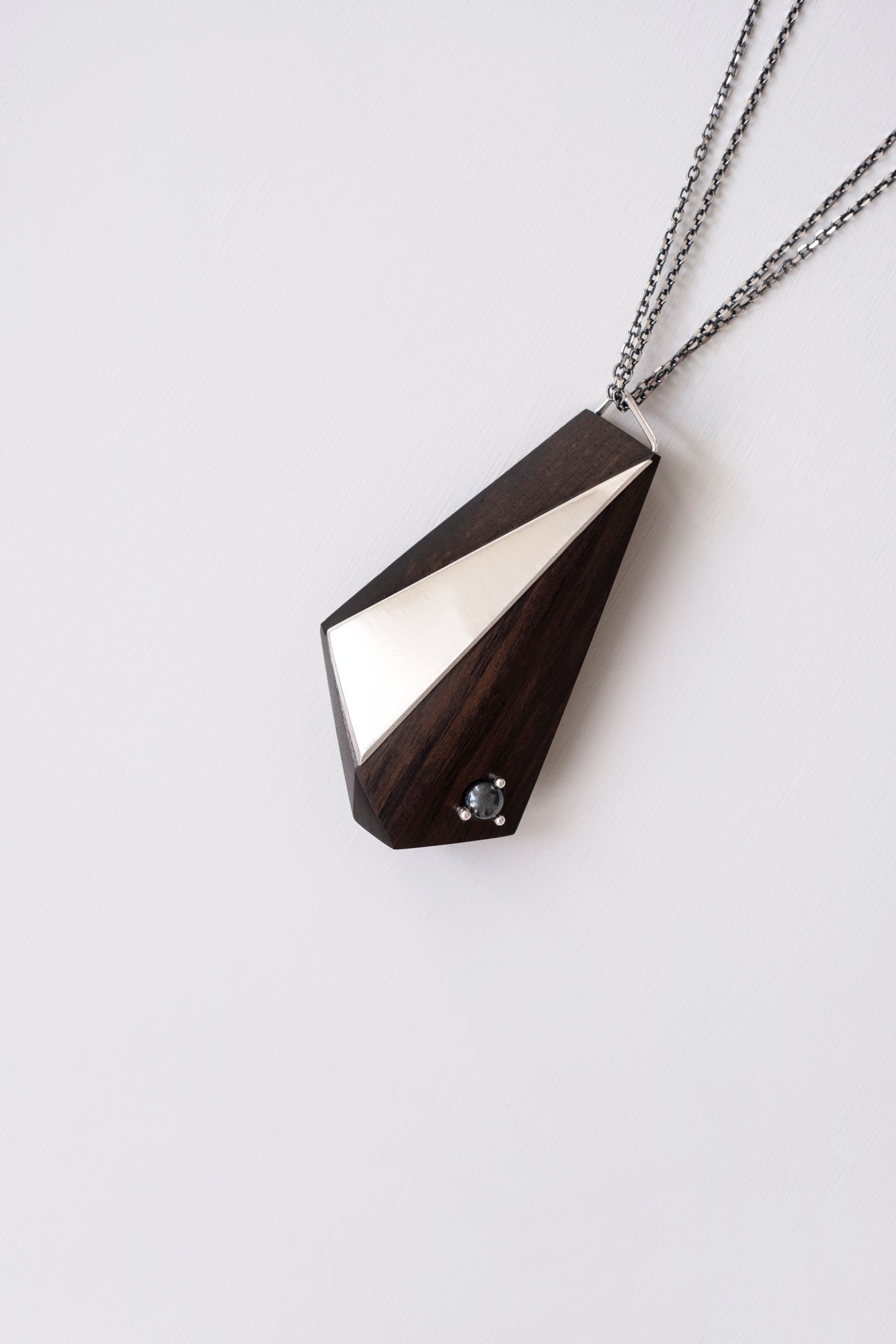 Blackwood Geometric pendant with silver and Hematite details with diagonal composition on a light gray background