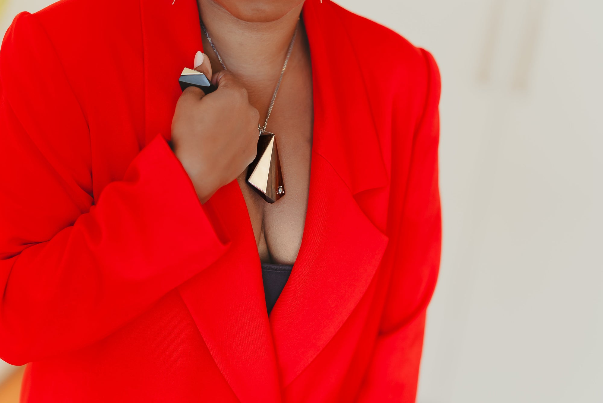 Large blackwood and silver geometric pendant on model wearing a red blazer and geometric black and silver ring.