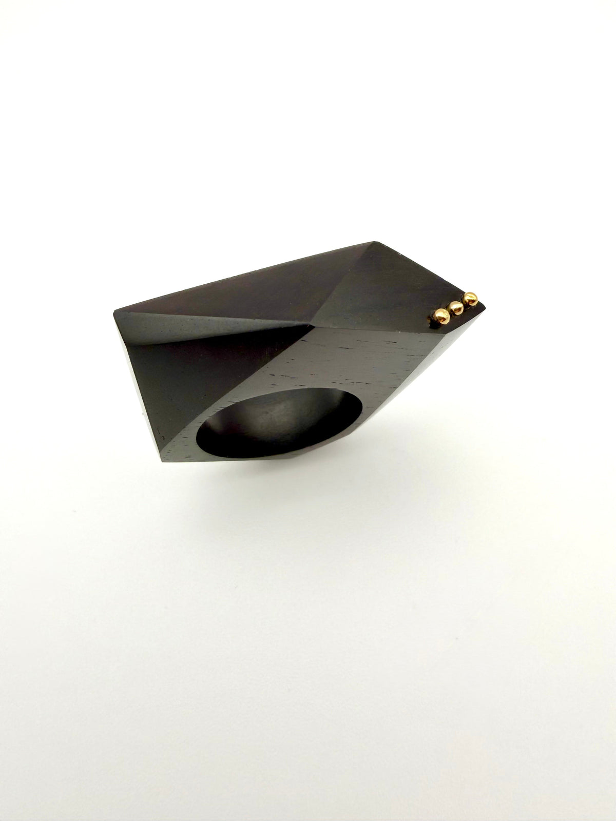 Black geometric sculpture ring with 3 dot gold detail on white background. 
