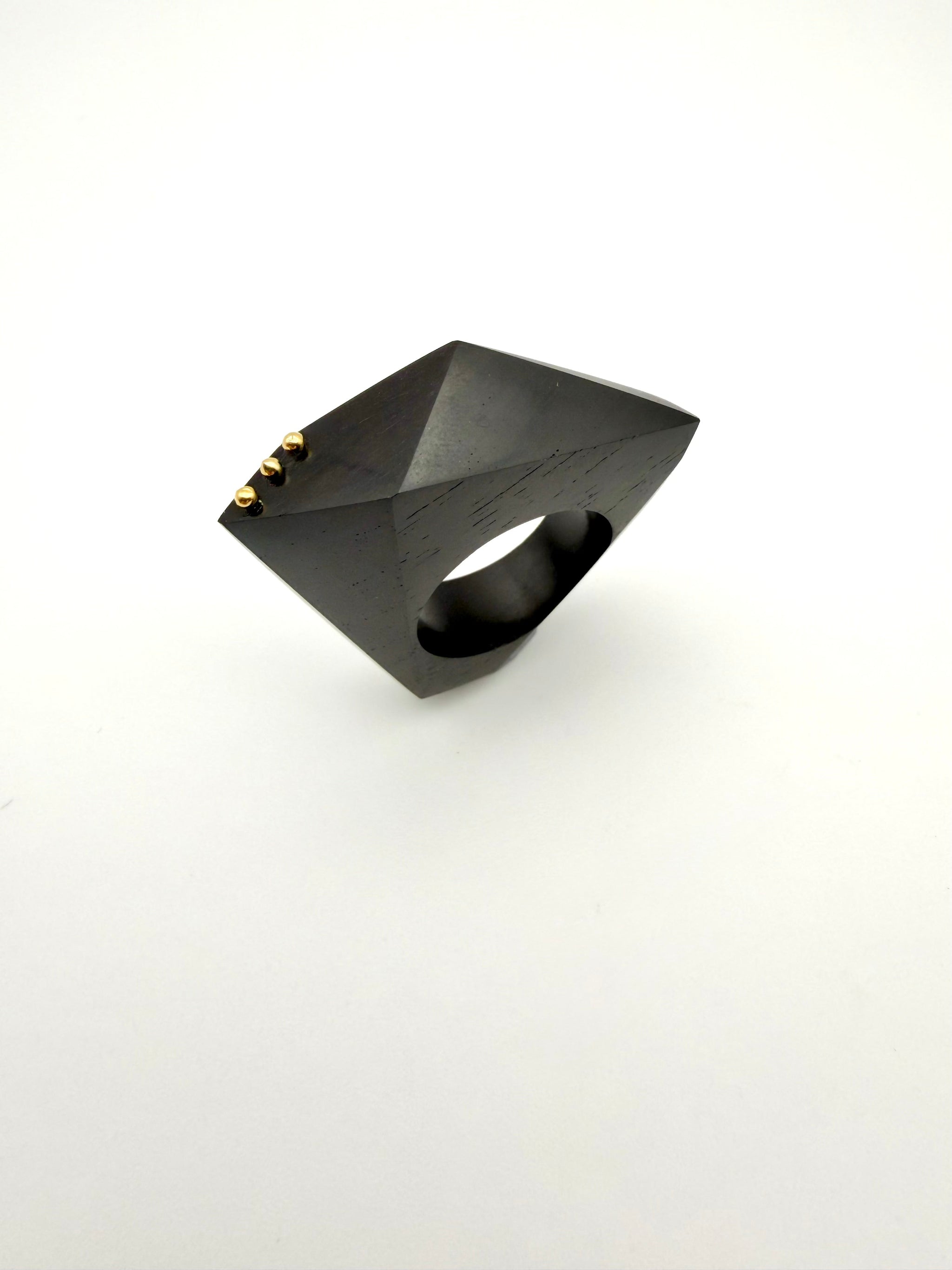 Black geometric ring with gold accents on a white background