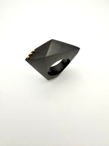 Black geometric ring with gold accents on a white background
