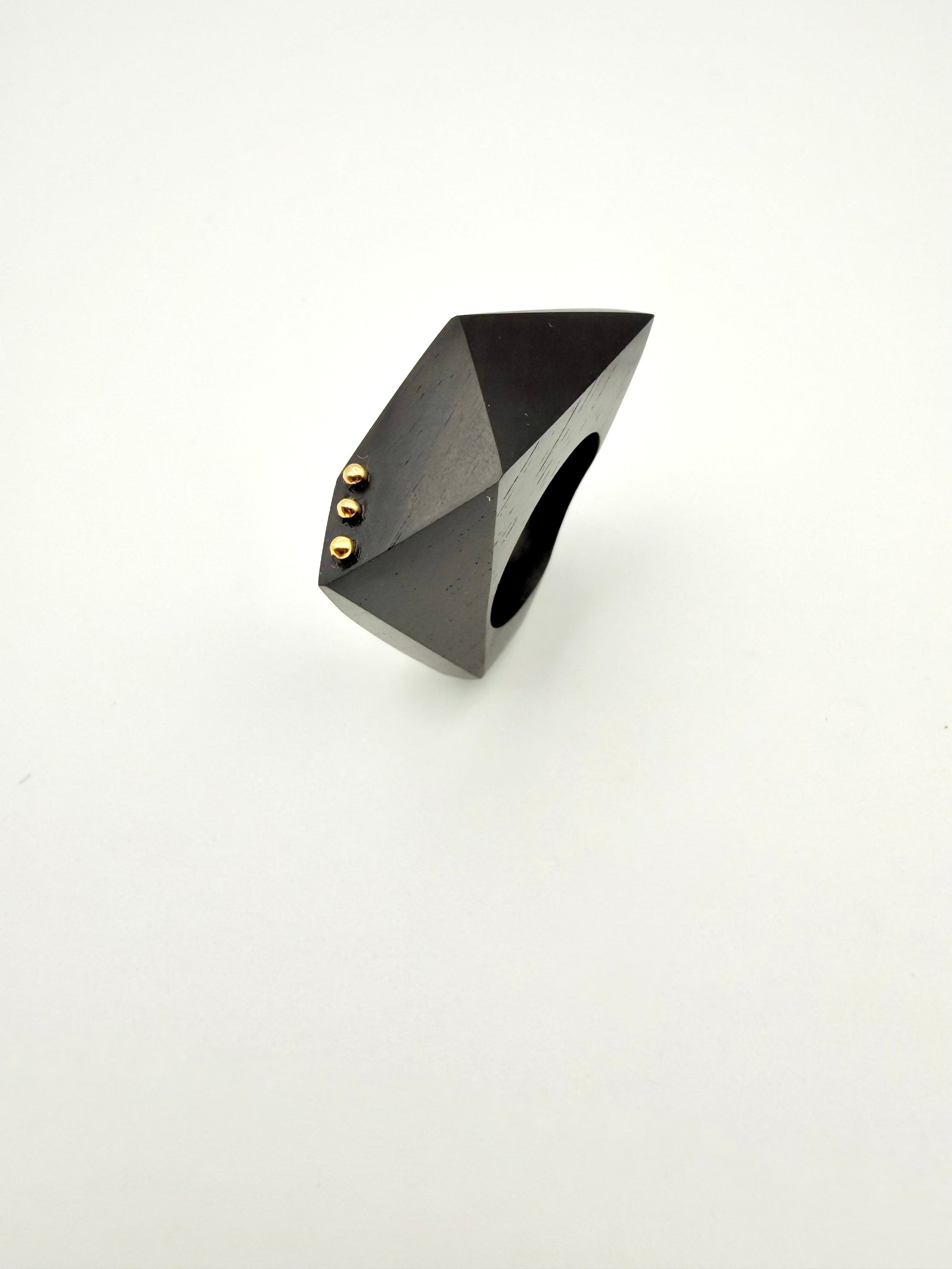 Black geometric ring with gold accents on a white background
