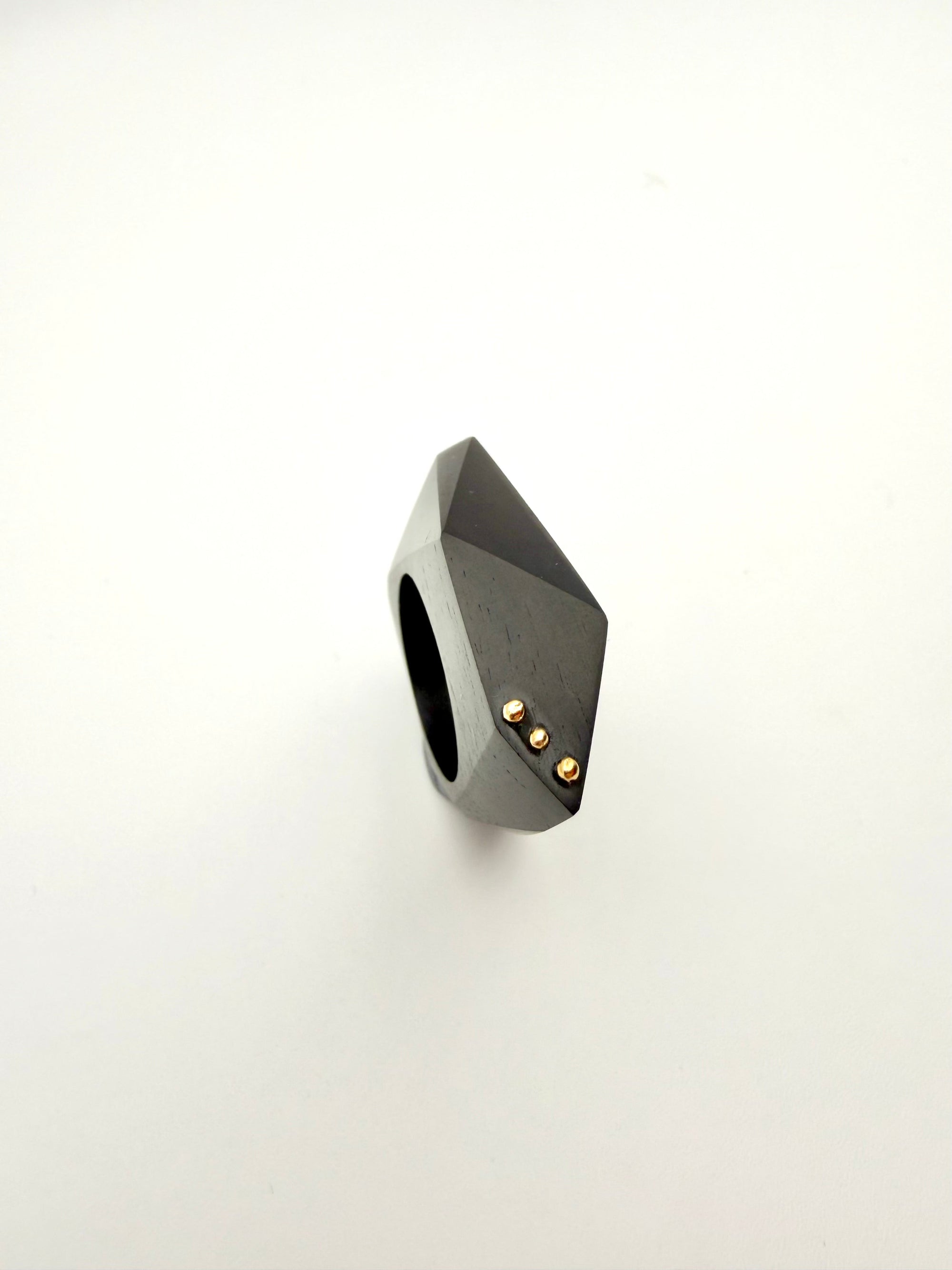 Geometric black ring with gold accents on a white background