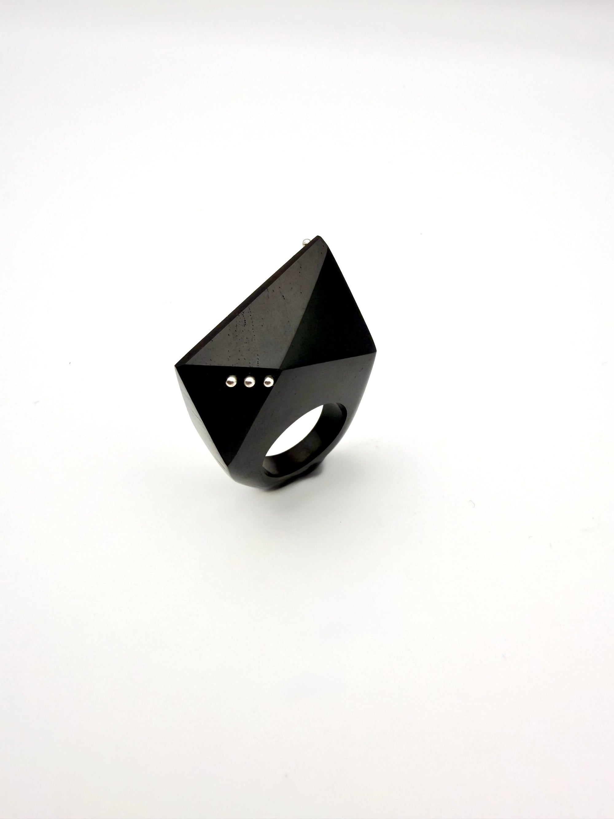 Black geometric ring with silver details on a white background