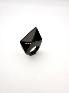 Black geometric ring with silver details on a white background