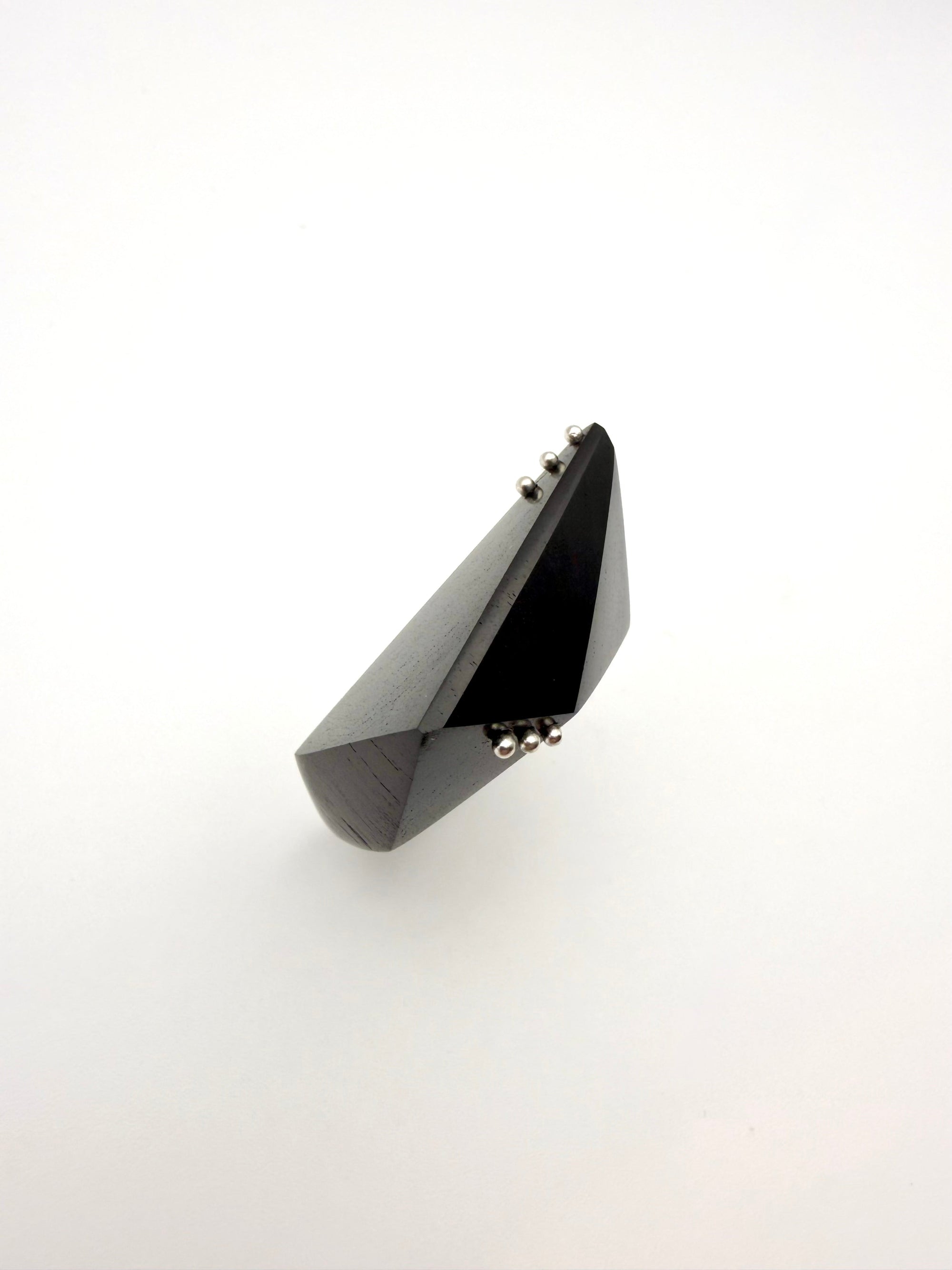 Black geometric wood ring with silver details on a white background
