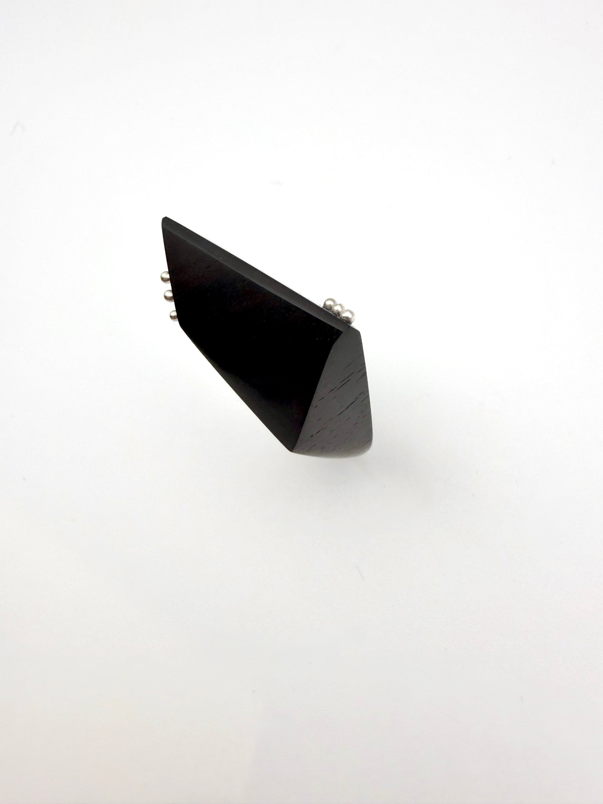 Black geometric ring with silver details on a white background