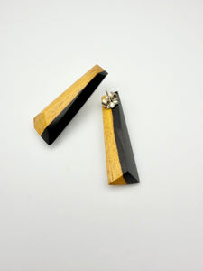 Pair of black and tan long wood stud earrings showing the back stud on one earring. 