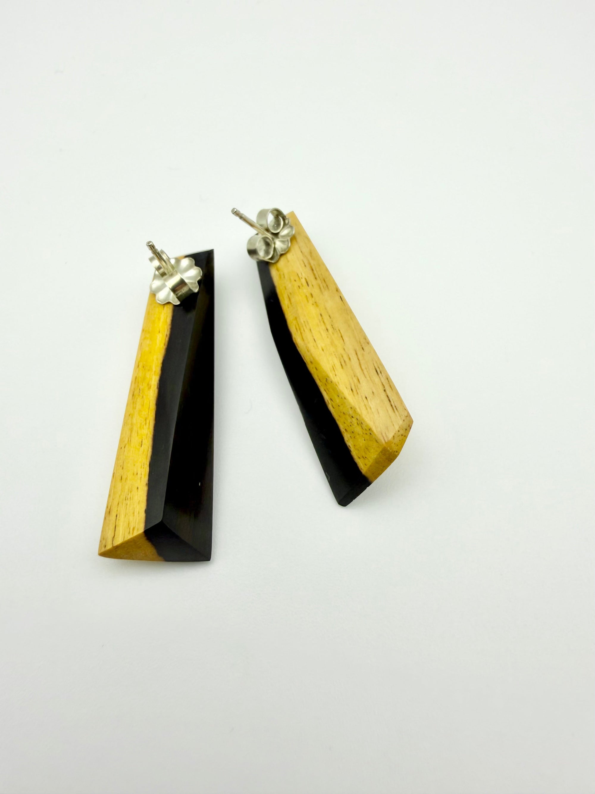 Back image of a pair of black and tan long wood stud earrings