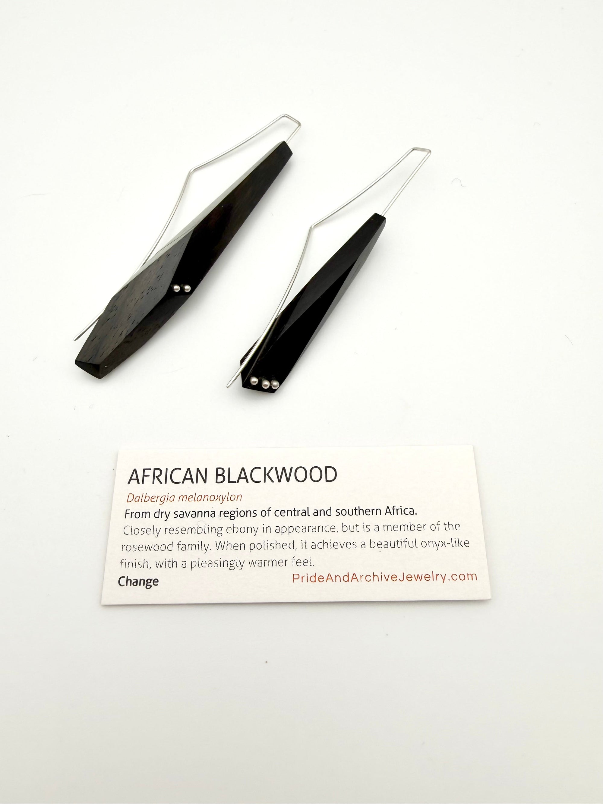 African Blackwood earrings next to a white card with details about the wood.