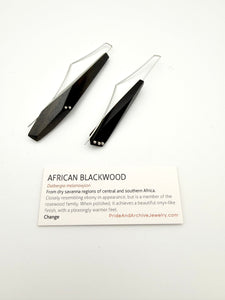 African Blackwood earrings next to a white card with details about the wood.