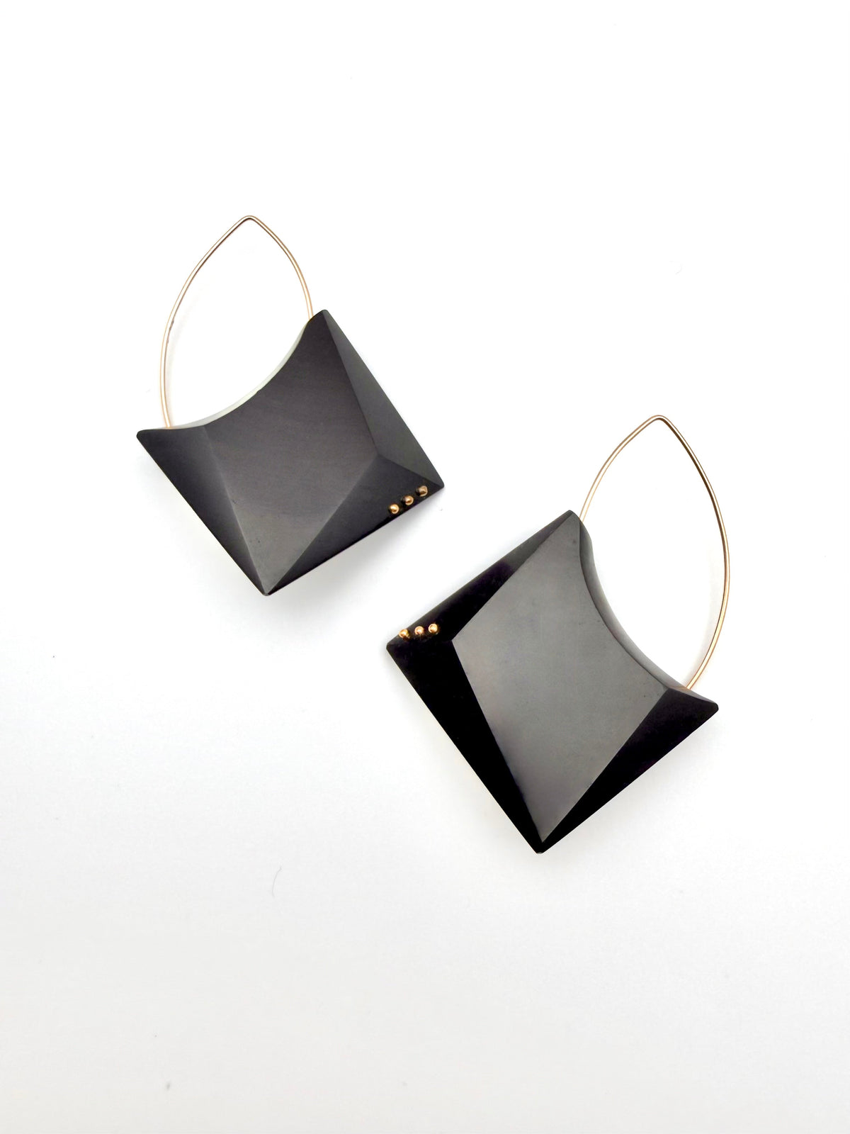 Pair of black earrings with gold loops on a white background
