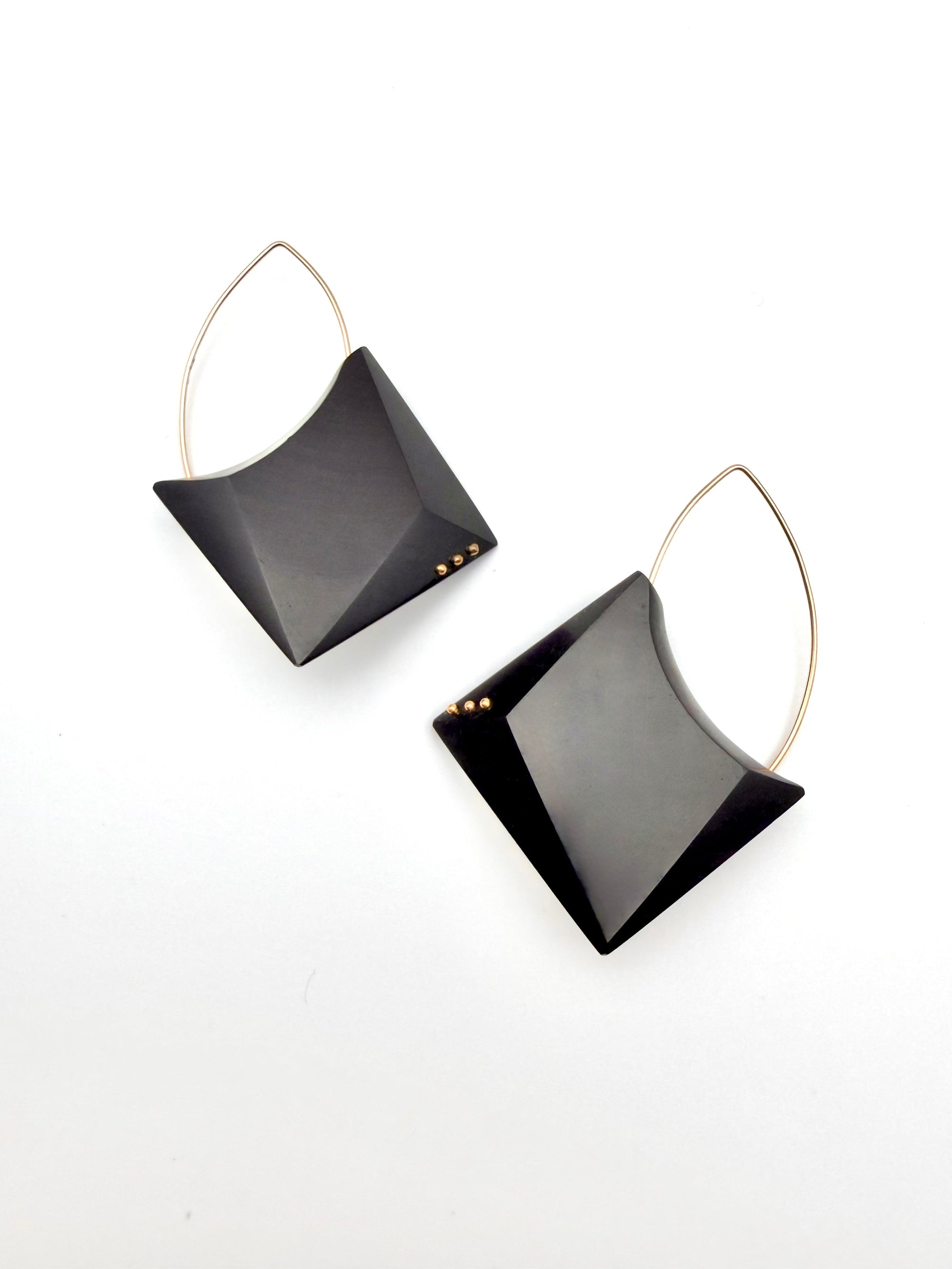 Pair of black earrings with gold loops on a white background