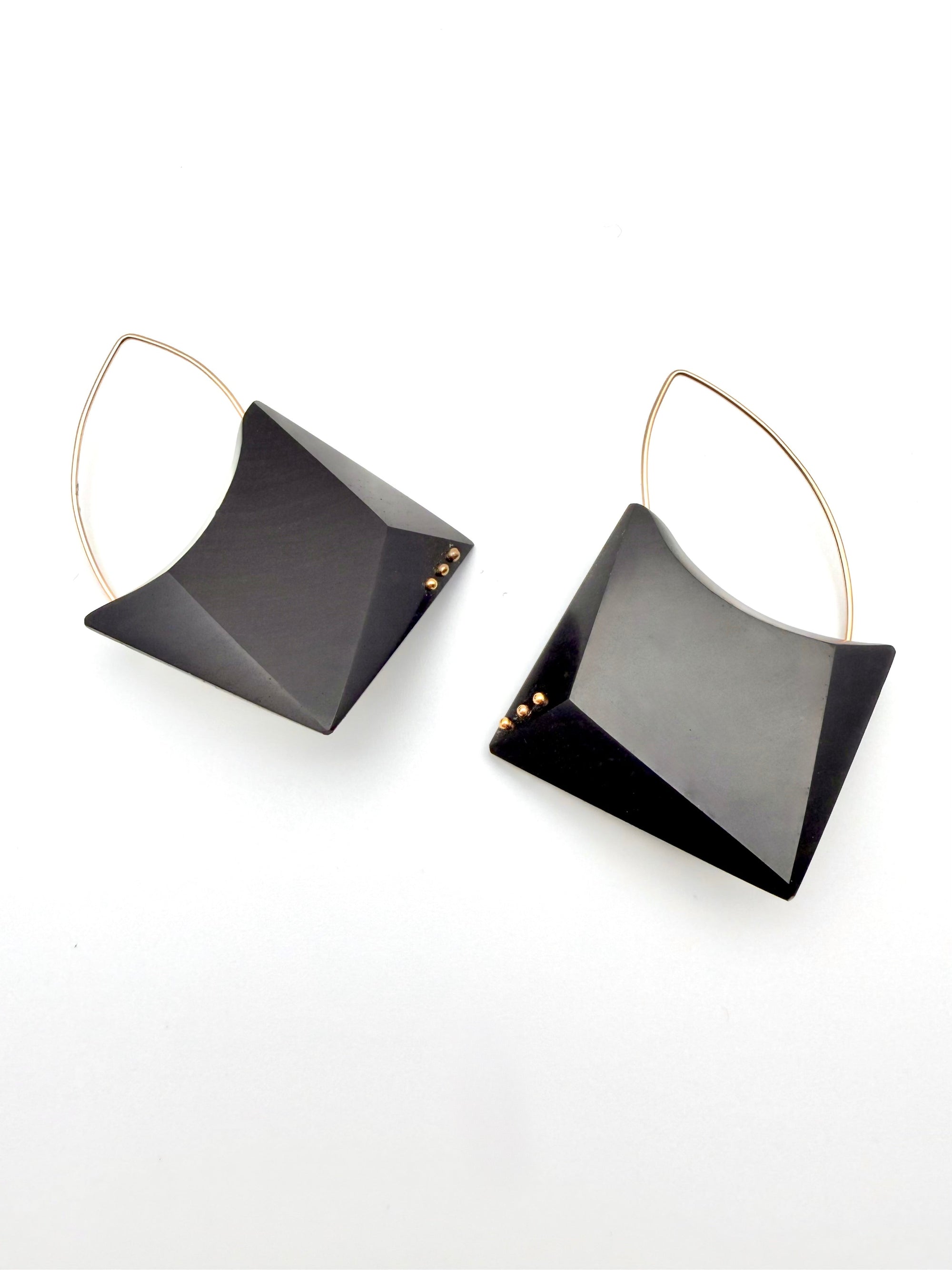 Pair of geometric black earrings with gold accents on a white background