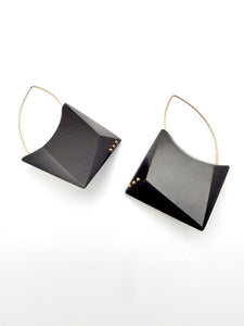 Pair of geometric black earrings with gold accents on a white background
