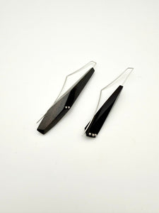 Long black asymmetric geometric pair of wood earrings with silver ear wires and dot details on a white background.