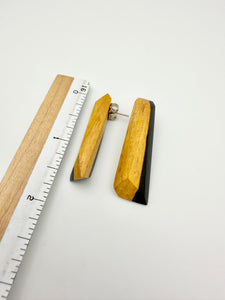 Pair of black and tan long wood stud earrings next to ruler to show scale about 1.5" long