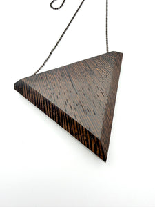 Detail back view of triangular pendant with wavy wood grain pattern on a white background 