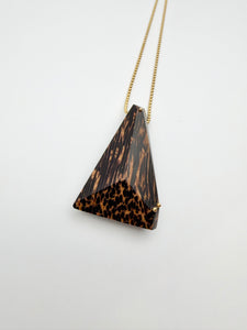 Triangular pendant with tortoiseshell pattern on a gold chain against a white background