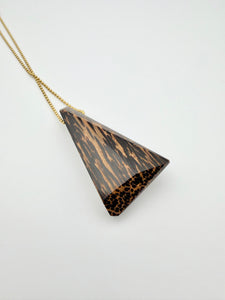Wood triangle pendant on gold chain with white background. 