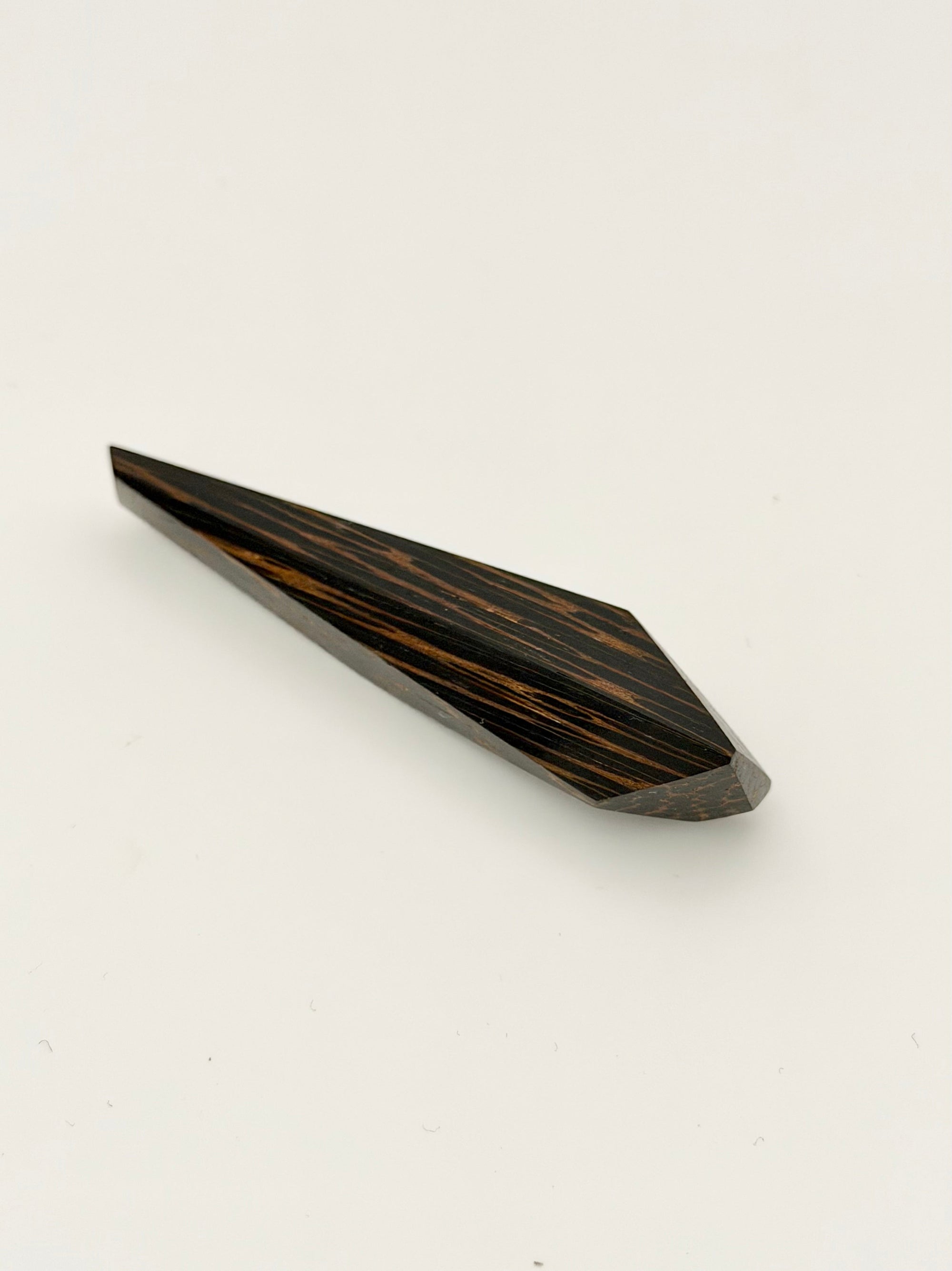 Black and brown geometric wood brooch on white background. 