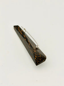 Black and brown geometric wood brooch with silver pin on white background. 