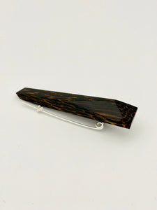 Black and brown geometric wood brooch on white background. 