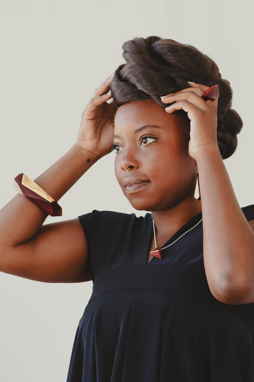 Model wearing wood and brass jewelry set including bangle, necklace, earrings and ring. 