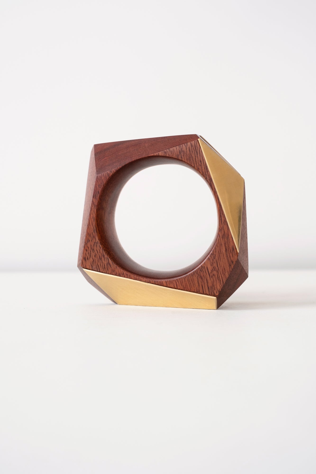 Wooden and brass geometric object on a white background