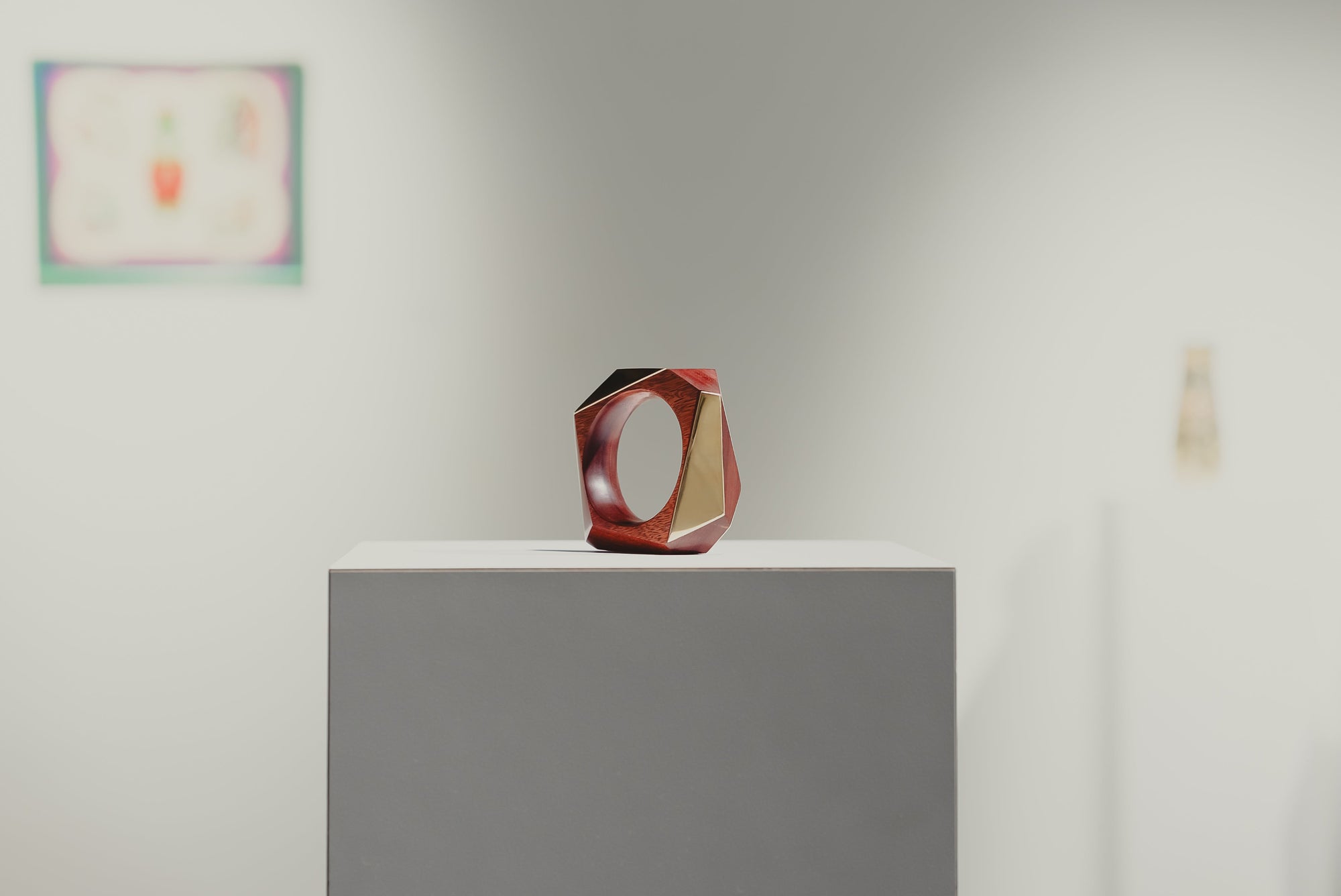 Wood and Brass bangle displayed on a pedestal in an art gallery displayed as a sculpture.  
