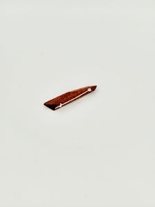 Back side of red geometric wood brooch on white background. 