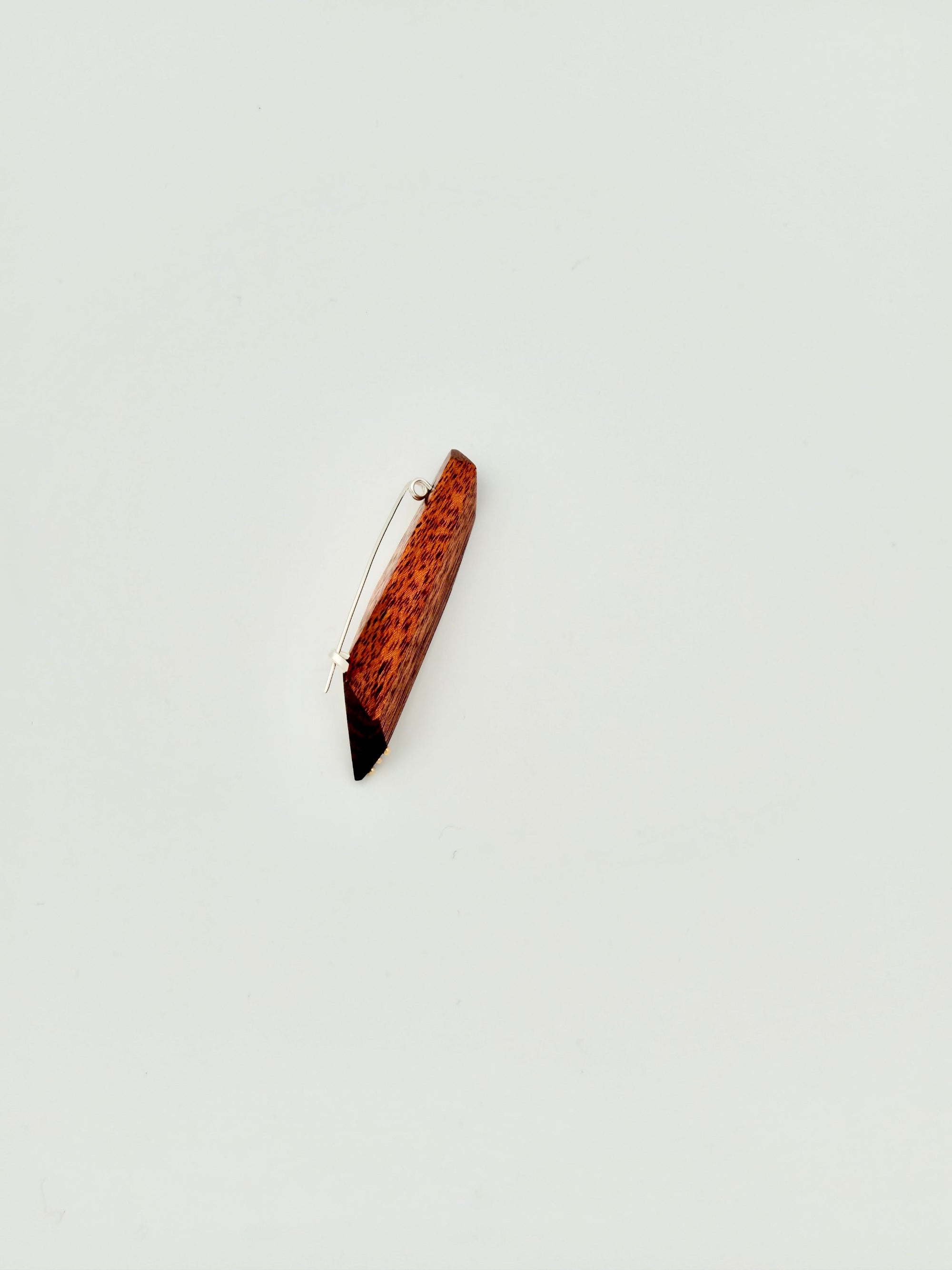 Side view of red geometric wood brooch with 3 dot gold details on white background. 
