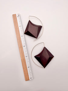 Deep red wood geometric earrings with Gold Filled Details and ear wires on a light background next to a ruler for scale. 