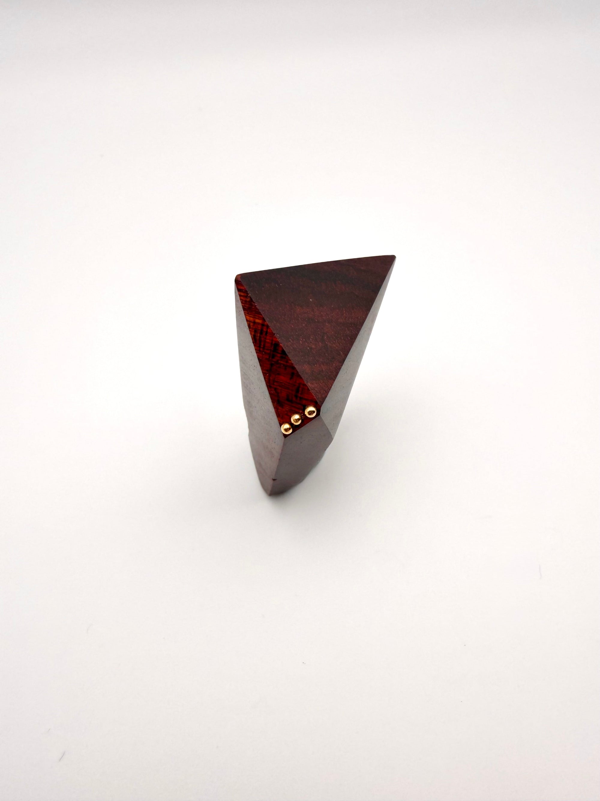 Triangular wooden object with gold accents on a white background