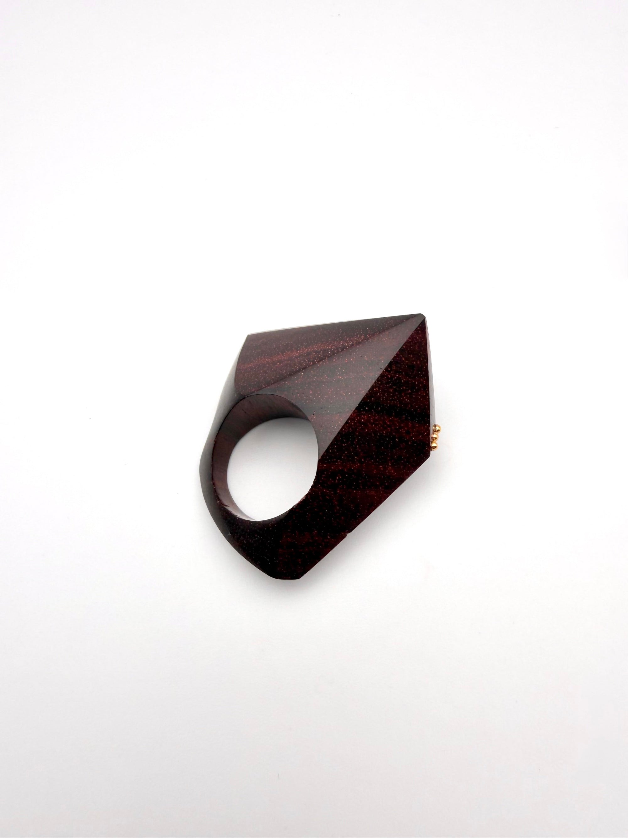 Geometric burgundy wood sculpture ring on a white background