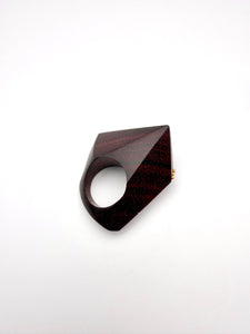 Geometric burgundy wood sculpture ring on a white background