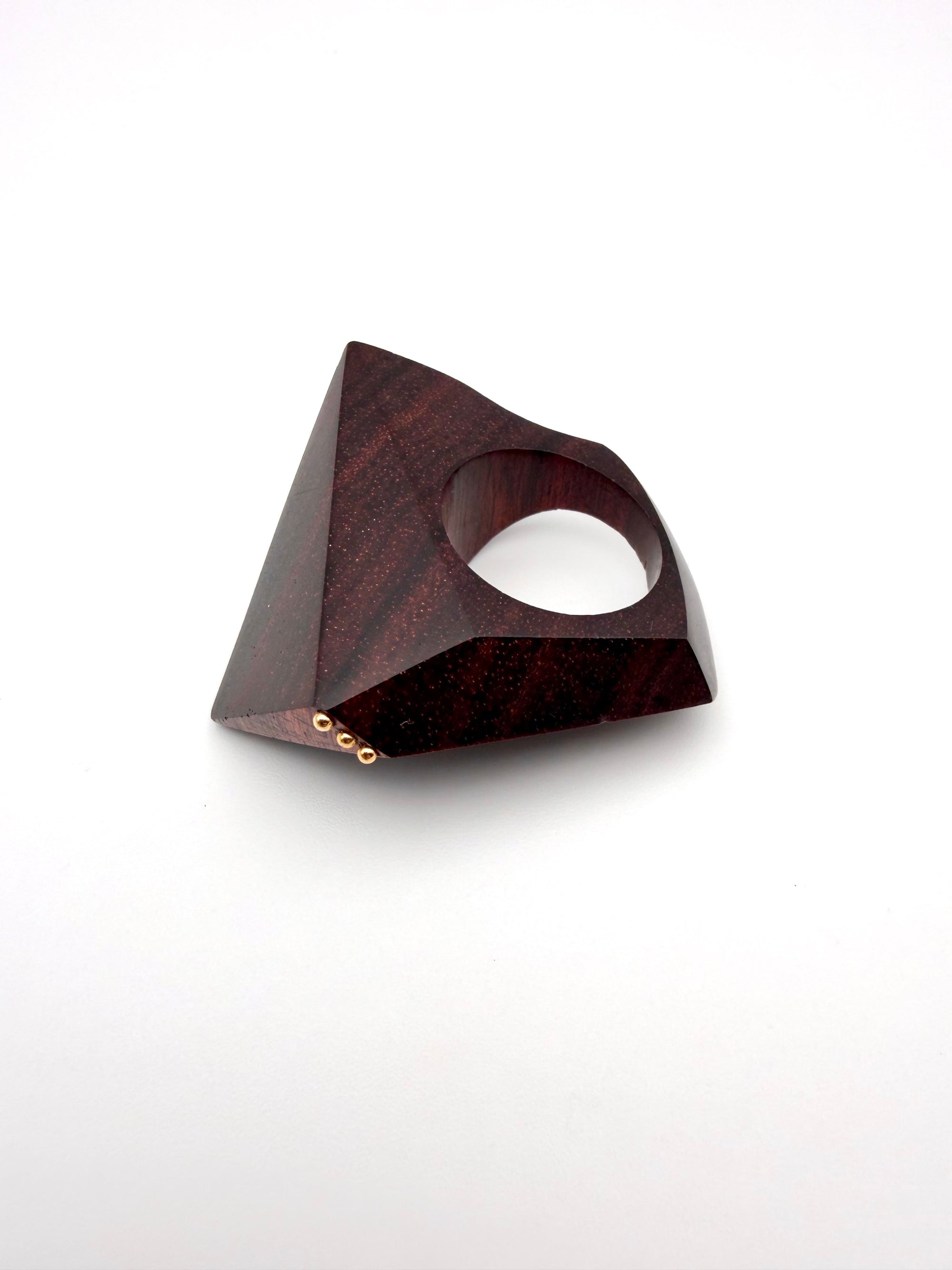 Geometric wooden object with 3 dot gold detail on a white background