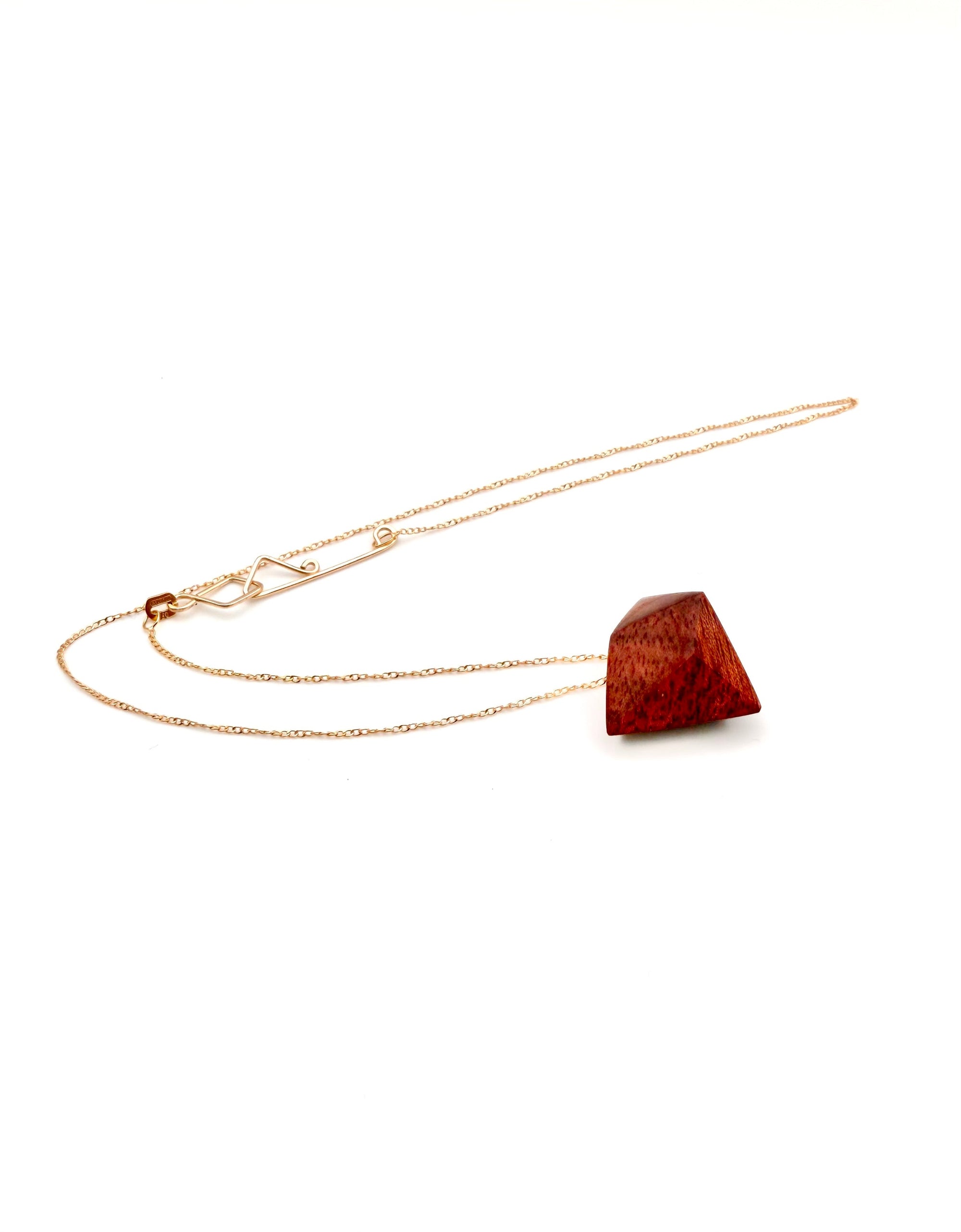 Gold chain with geometric wood pendant  necklace. Looks like a red stone pendant on a white background