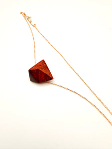 Necklace with a burgundy/red wood geometric pendant on a white background