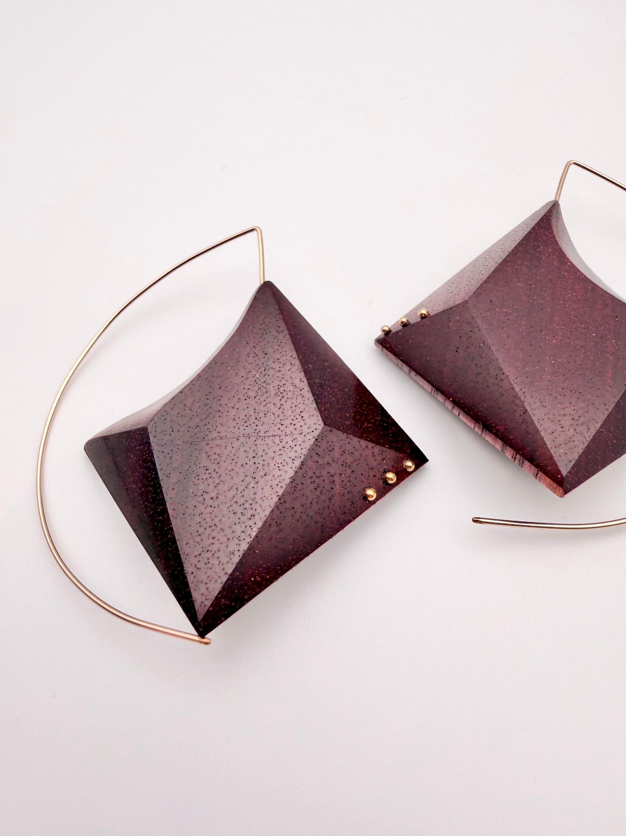 Geometric dark red wood earrings with a gold hoop and 3 dot detail on each earring on a light gray background