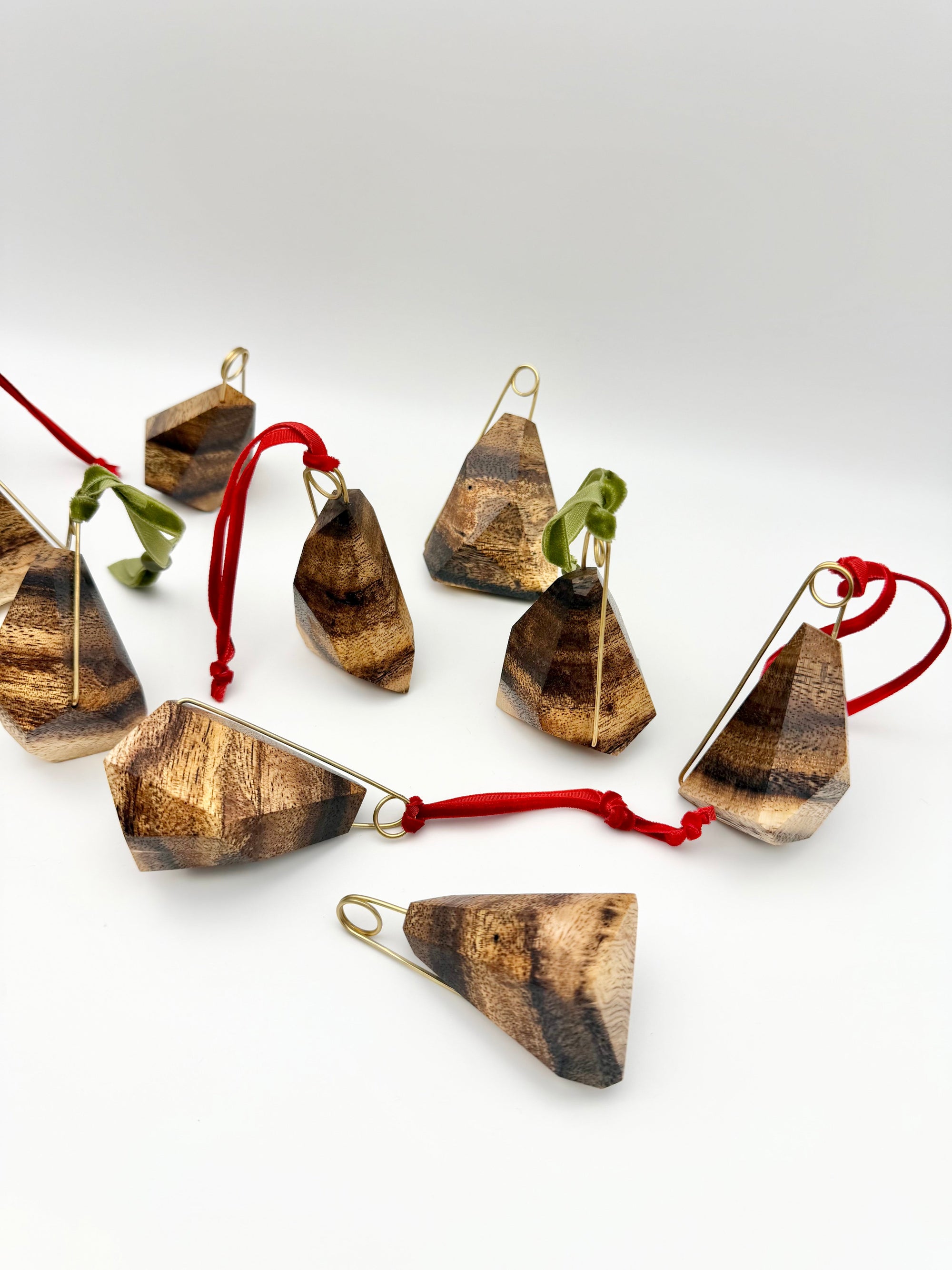 Wood and brass ornaments with red & green ribbons on a white background