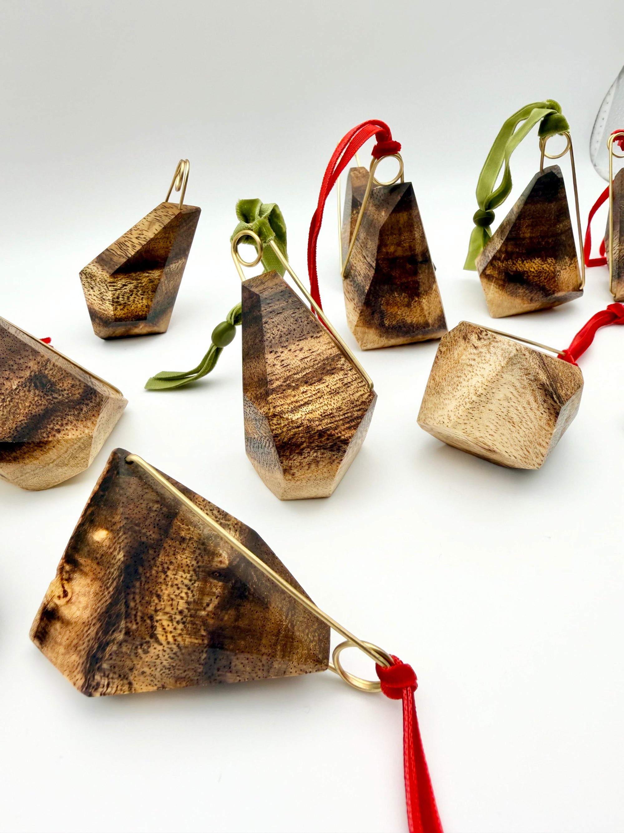 Wooden geometric ornaments with red and green ribbons on a white background