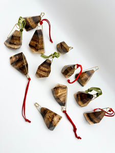 Geometric Wood Ornaments with brass details and red and green ribbons on a white background. 