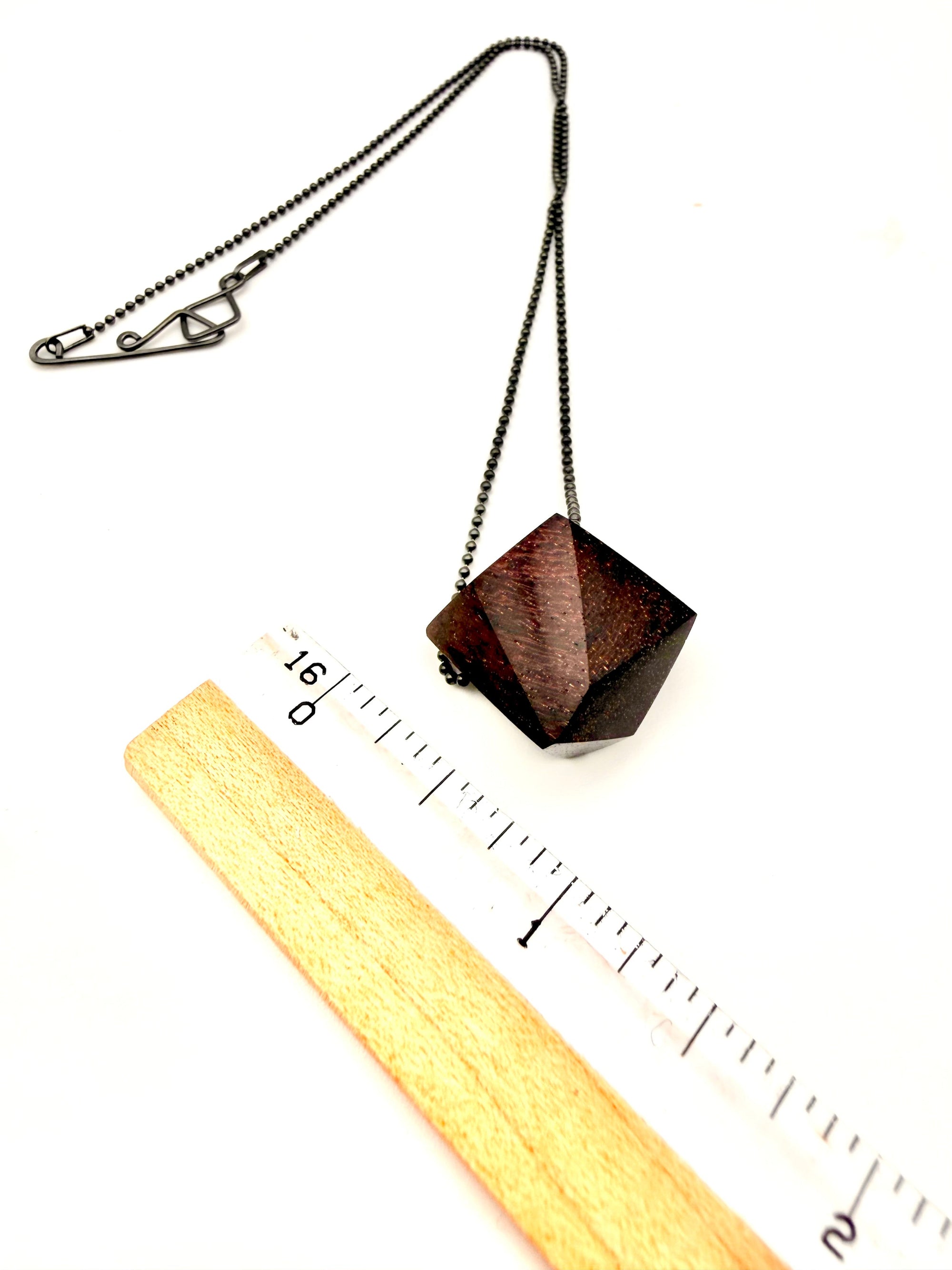 Geometric wood pendant necklace with Oxidized Silver Ball Chain next to ruler for scale on a white background