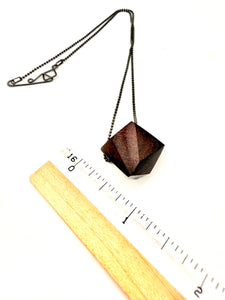 Geometric wood pendant necklace with Oxidized Silver Ball Chain next to ruler for scale on a white background
