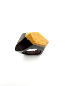 Two-tone ring with black and gold geometric design on a white background