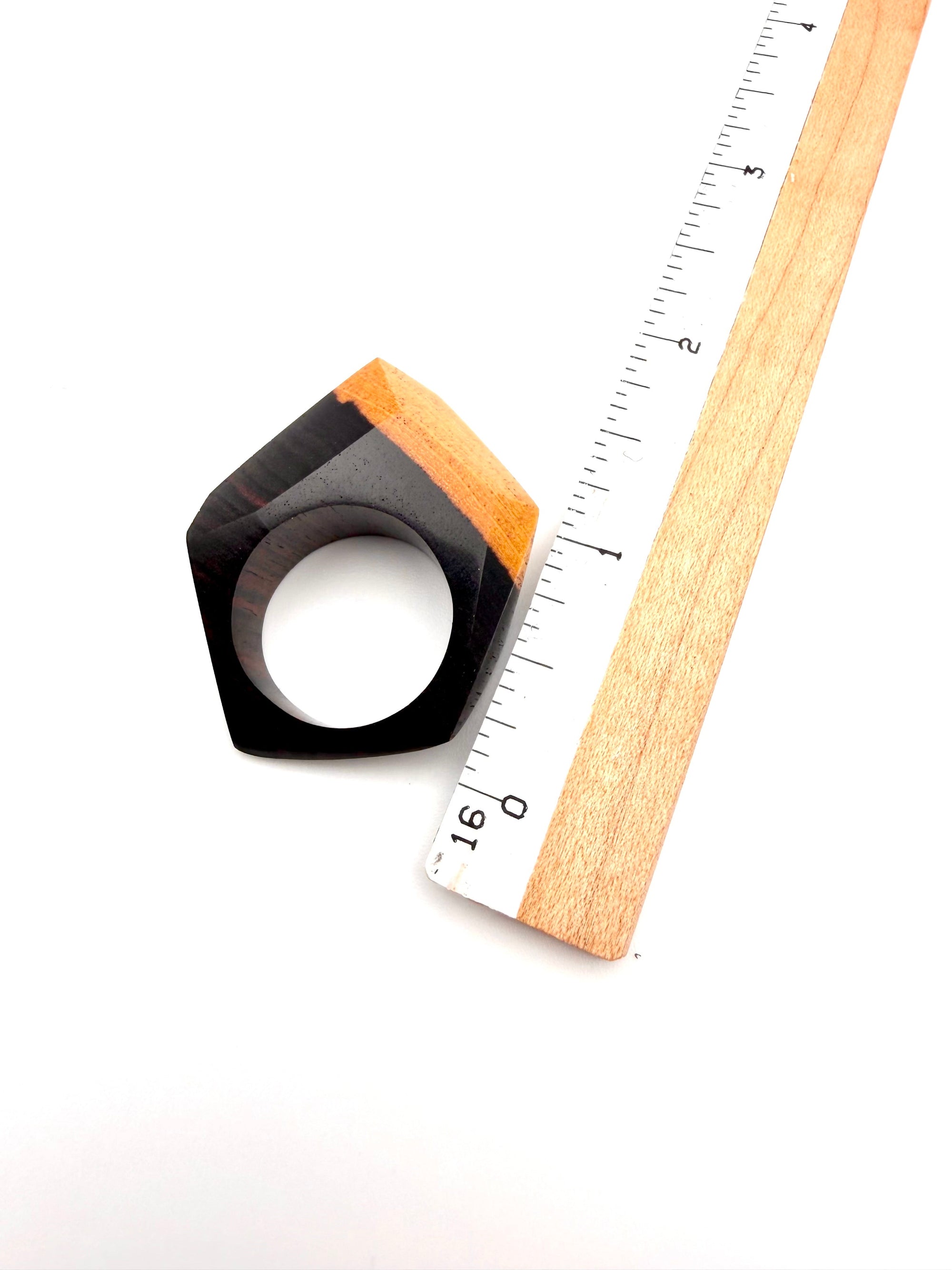 Wood geometric ring next to a ruler on a white background