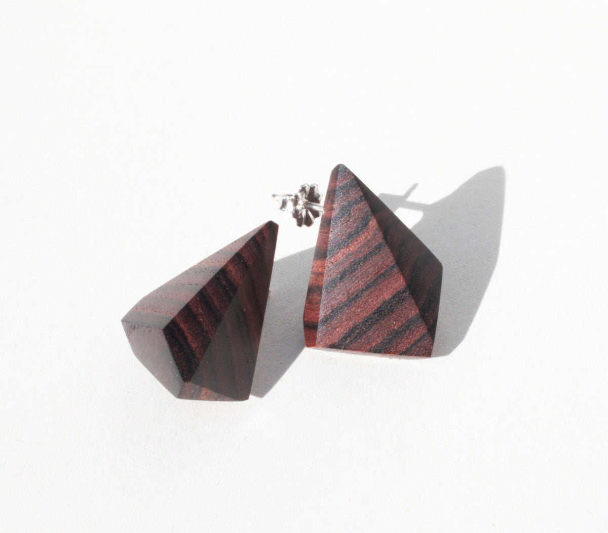 Geometric wood earrings with silver stud showing. 
